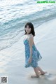 A woman in a blue dress standing on a beach.