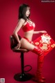 A woman in a red lingerie sitting on a stool.