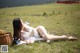 A woman in a white bikini laying on a grassy field.