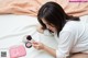 A woman sitting on a bed holding a makeup brush.