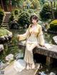 A woman in a yellow kimono sitting on a wooden bridge.