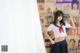 A woman in a school uniform posing in front of a wall of magazines.