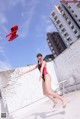 A woman in a red and black bathing suit jumping in the air.