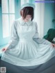 A woman in a white dress sitting on a window sill.