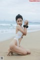 A woman in a white bathing suit sitting on the beach.