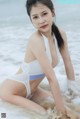 A woman in a white bikini sitting in the water.