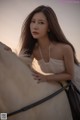 A woman in a white dress sitting on top of a white horse.