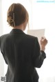 A woman in a business suit writing on a piece of paper.