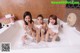 A group of three young women taking a bath in a bathtub.