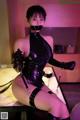 A woman in a black latex outfit is tied up and gagged.