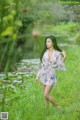 A woman in a pink dress standing in a field of tall grass.